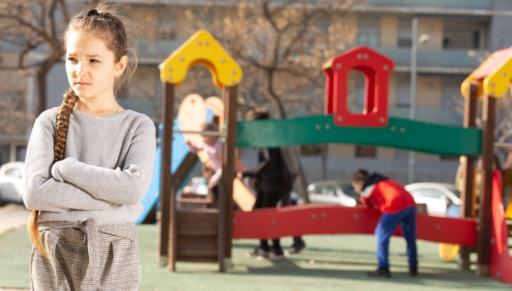 child with social anxiety standing alone on a playground