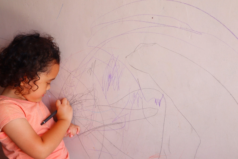 picture of little girl scribbling on the wall